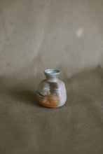 Load image into Gallery viewer,  small white and orange bud vase on a beige fabric background. The piece is made from white Australian stoneware clay flame markings on one side. 