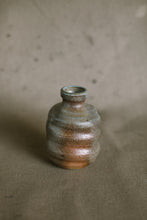 Load image into Gallery viewer, A green and brown wood fired vase on a beige fabric background. This wheel thrown and altered flower vase is made from sandy orange Australian stoneware clay with Iight green wood ash.