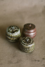 Load image into Gallery viewer, Three brown and green small wood fired jars on a beige fabric background. These wheel thrown jars are made from iron rich Australian stoneware clay with dark green heavy wood ash covering two