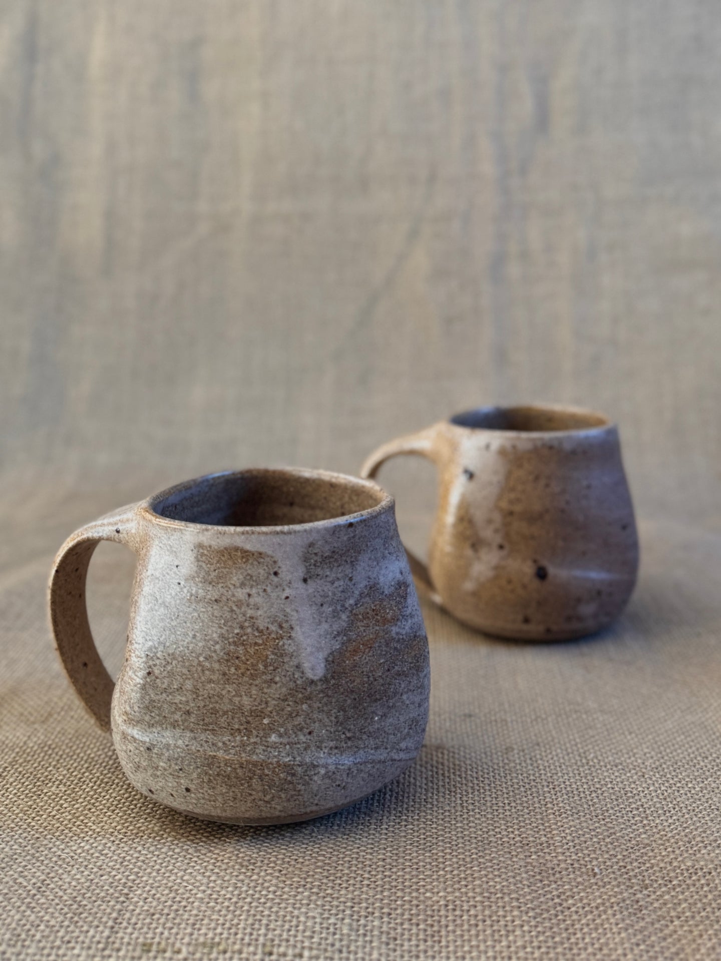 Two ceramic mugs on a textured beige surface