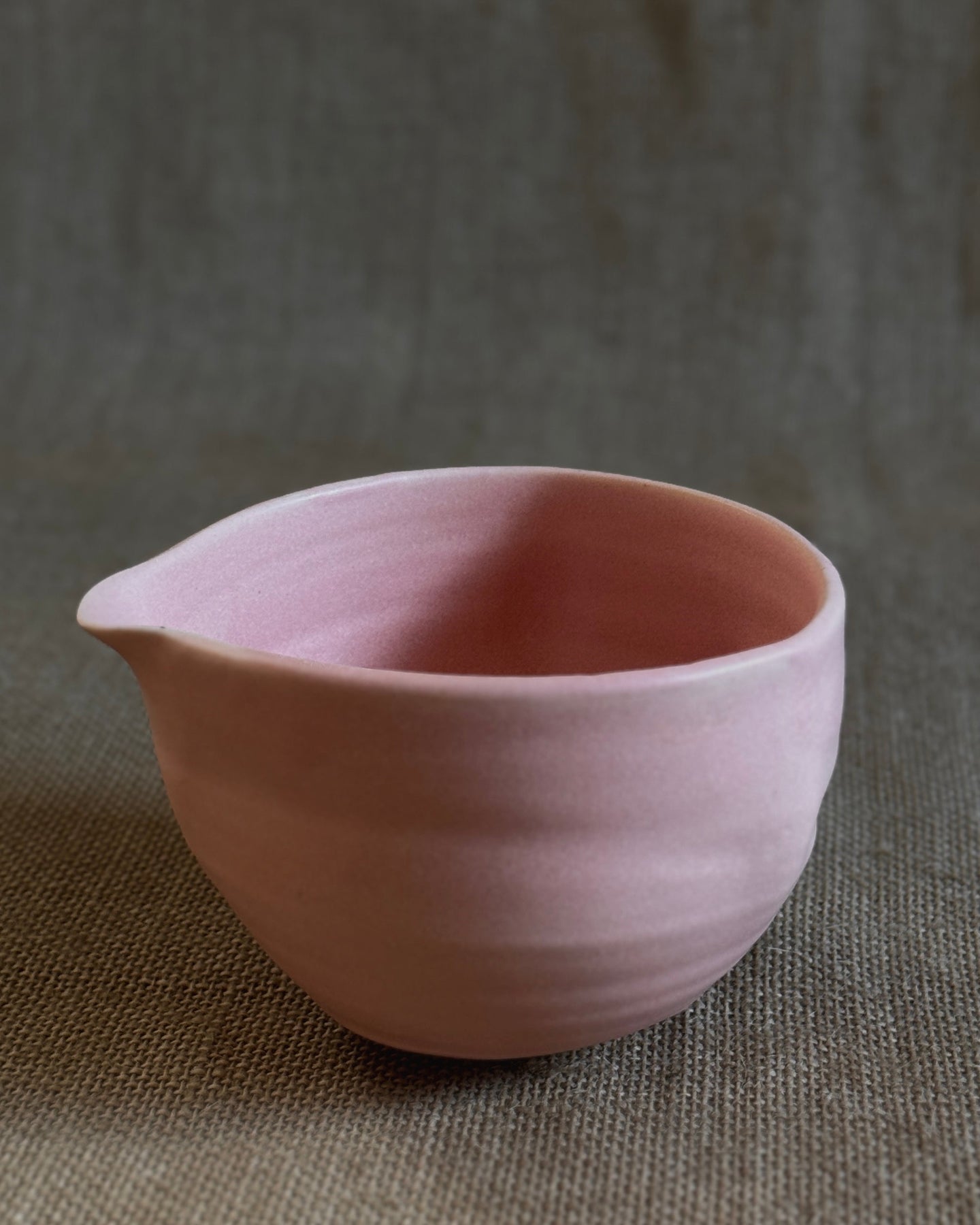 Pink ceramic matcha bowl on a textured brown surface