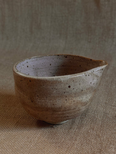 Stoneware matcha bowl with speckled texture on a beige fabric background