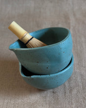 Load image into Gallery viewer, Teal ceramic matcha bowl with a Chasen (bamboo whisk) on a textured fabric background