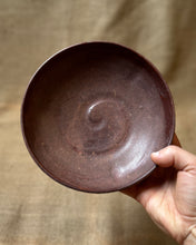 Load image into Gallery viewer, A ceramic pasta bowl with a dark red matte glaze being held up against a neutral background