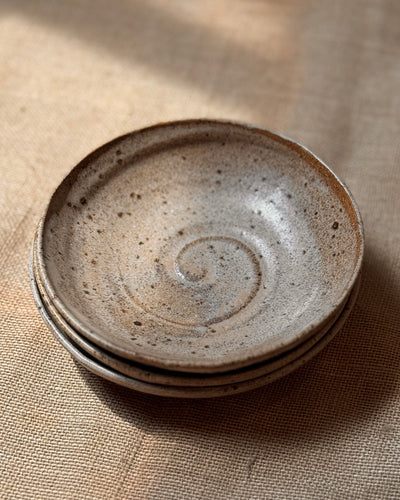 Stack of ceramic stoneware pasta bowls with a spiral design glazed in a speckle beige colour 