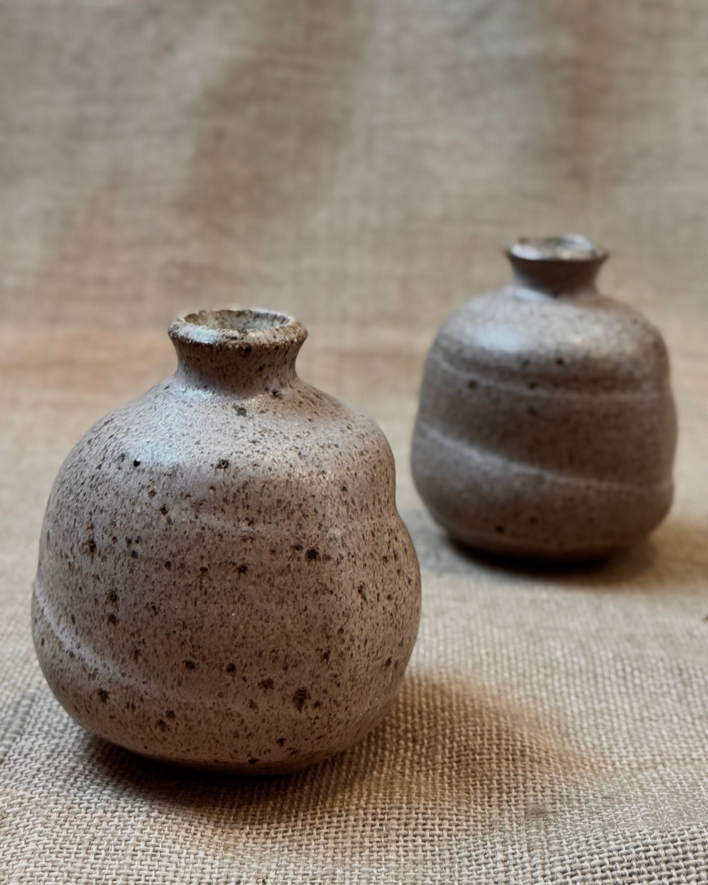 Two small ceramic bud vases with a beige speckled glaze