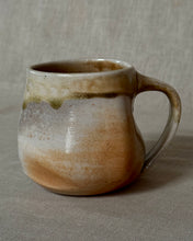Load image into Gallery viewer, Woodfired ceramic mug with carbon trapping and ash glaze on a linen background