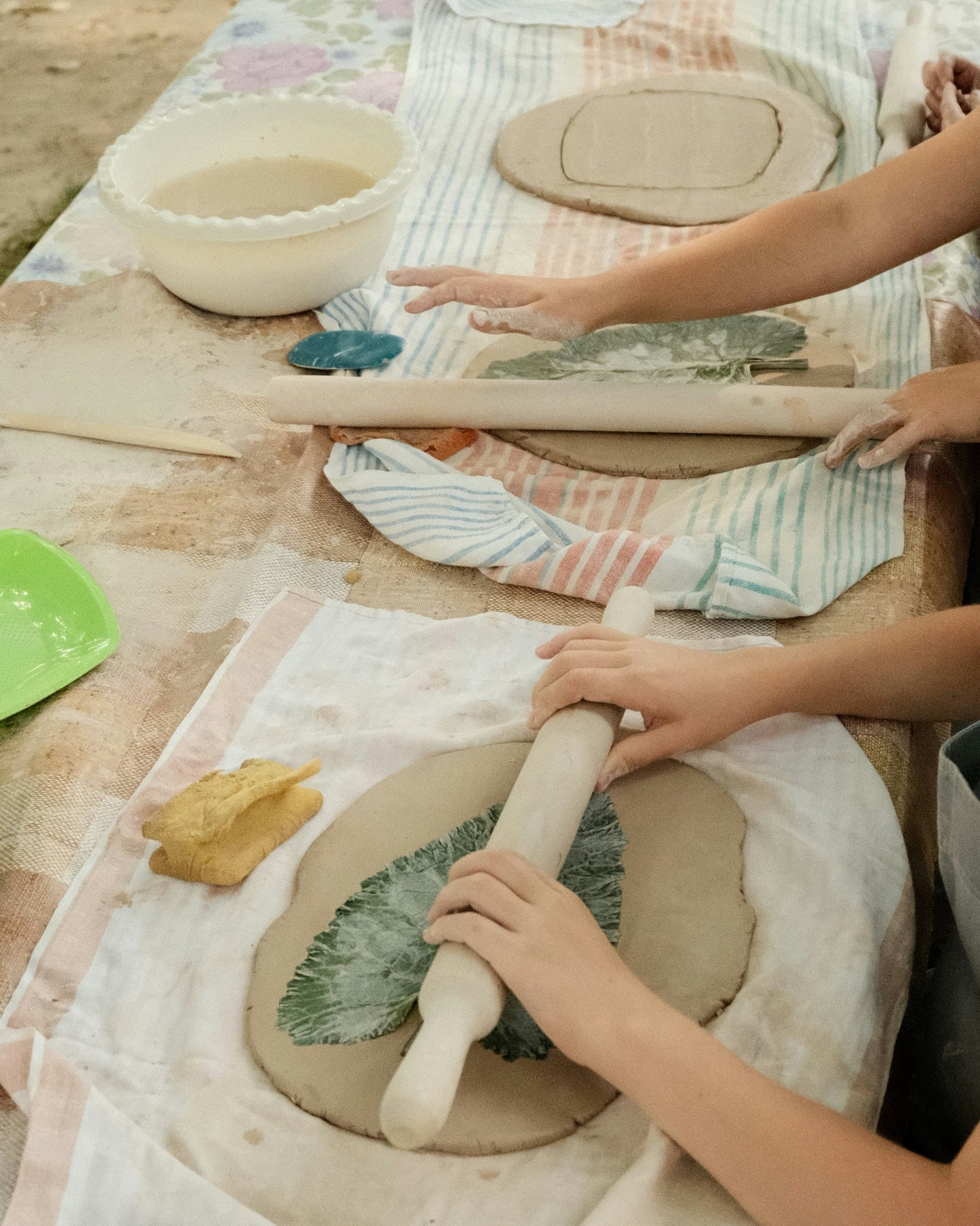 Two children rolling out clay in a kids pottery class