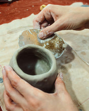 Load image into Gallery viewer, Person smoothing a small clay pot