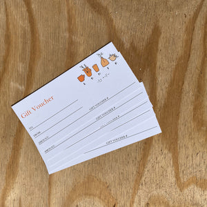 A blank paper gift voucher with the Lunio by Sofie logo, resting on a piece of pale wood. 